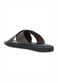 Infradito marrone con due cinturini sovrapposti, larghi. Materiale morbido, design flessibile, suola testurizzata e pianta piatta per il massimo comfort.