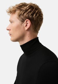 Schwarzer Rollkragenpullover mit tailliertem Design, geripptem Kragen und glatter Textur, der einen minimalistischen Stil zeigt. Seitenansicht.
