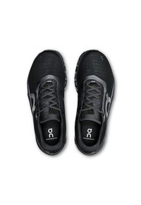 Schwarze Sportschuhe mitMesh-Obermaterial, ausgestattet mit grauen Akzenten und Schnürsenkeln, gepolsterten Sohlen und dem auf den Innensohlen aufgedruckten Logo.