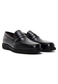 Black leather loafers with a textured upper, smooth band across the instep, and a low flat sole. Clean lines and minimalistic design.