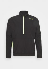 Svart lättviktsjacka med halvdragkedja, hög krage och reflexorangea detaljer på dragkedjan och sidorna. Har elastiska ärmslut och nederkant.