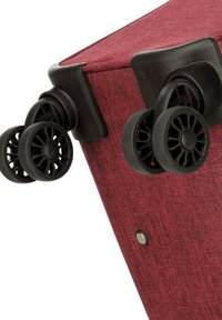 Coin de valise en tissu rouge avec des roues noires en plastique, surfaces lisses et un rivet rond argenté. Fini texturé et conception robuste.