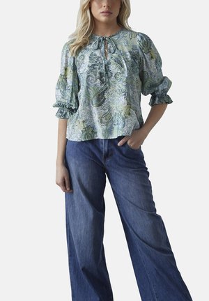 Lys blå paisley bluse med puffede ærmer, bindebånd ved halsen og elastiske manchetter, parret med brede denim jeans. Blødt stof tekstur.