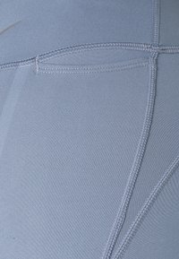 Jasnoniebieskie legginsy sportowe wykonane z gładkiego, elastycznego materiału, z płaskimi szwami i panelem dla lepszego dopasowania i komfortu.