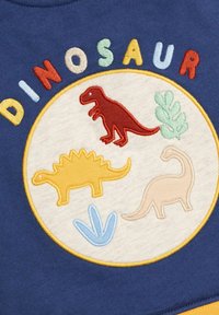 Námornícky sveter so vyšitým kruhovým motívom štyroch farebných dinosaurov (červený, žltý, béžový) a zelenými akcentmi lístia.