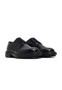 Chaussures en cuir noir avec une finition brillante, à bout rond, et une semelle en caoutchouc robuste présentant des rainures profondes. Design à lacets avec six œillets.