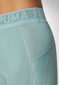 Jasnoniebieskie legginsy sportowe z teksturowanym pasem, kieszonką po boku oraz gładkim materiałem z delikatnym wzorem.