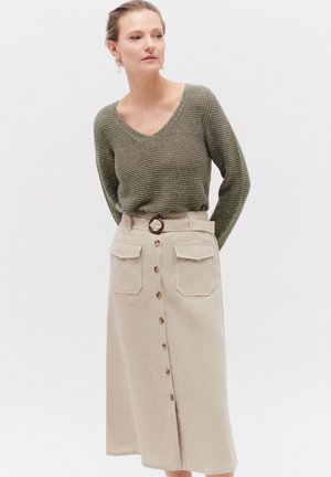 Olive green striped knit sweater with a V-neck, paired with a beige midi skirt featuring front button closure and two large pockets.