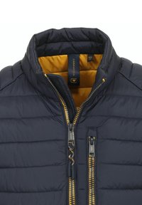 Marinblå puffjacka med en gul inredning, som har en hög krage och dubbel dragkedja framtill. Texturerad kviltad design genom hela jackan.