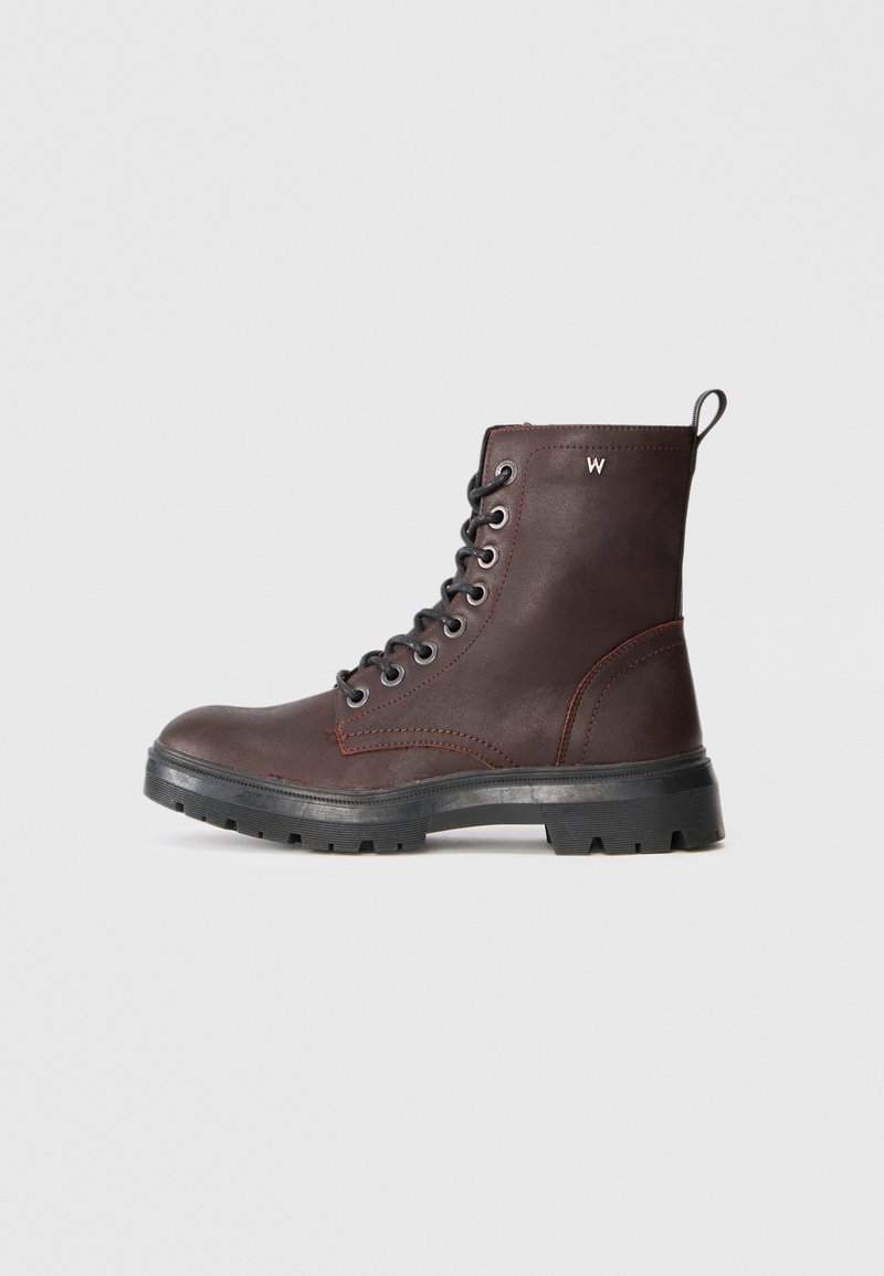 Brune lær ankle boot med metalløye, svarte snøres, kraftig såle og røde sømaksenter. Liten løkke på hælen for hjelp.