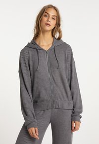 Šedá mikina na zip s žebrovanou texturou, oversized střih, přední kapsy, kapuce se šňůrkou a manžetami. Spárována s odpovídajícími žebrovanými kalhotami.