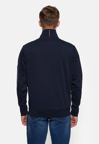 Dunkelblaues Sweatshirt mit Stehkragen, weichem Material und Reißverschluss am Hals, versehen mit gerippten Bündchen und Saum, designed für Komfort und Wärme.