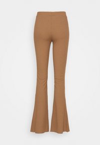 Pantalon évasé marron côtelé avec une taille haute. Texture lisse et silhouette ajustée, s'évasant vers un ourlet large aux chevilles.