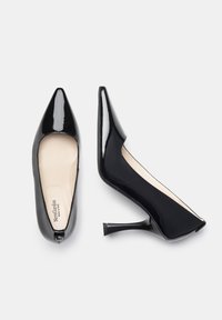 Zapatos de tacón alto de charol negro con un diseño de punta afilada, tacón delgado y textura suave. El interior presenta una plantilla de color beige claro.