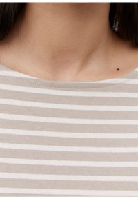 Pasek z miękkiego, lekkiego materiału. Posiada naprzemiennie ułożone beżowe i białe paski, szeroki dekolt oraz widoczne detale szycia.