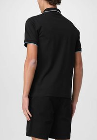 Polo shirt nera con maniche corte, con un bordo blu a contrasto sul colletto e sui polsini. Il tessuto sembra liscio e leggero.