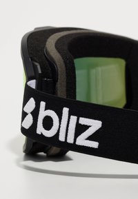 Sorte skibriller med tyk skumpolstring, grønne linser og et bredt sort rem med hvid tekst "bliz." Glat og robust ramme.