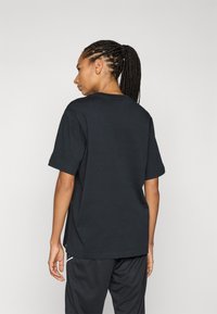 Black cotton t-shirt with a relaxed fit, short sleeves, and a classic crew neckline, featuring minimal design and no prominent patterns.