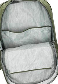 Das Innere des grünen Rucksacks verfügt über ein hellgraues Futter mit einem strukturierten Muster, zwei Taschen und ein großes Fach.