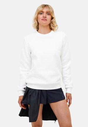 White sweatshirt with a crew neck and ribbed cuffs, paired with dark athletic shorts featuring an overlay and side zipper detail.