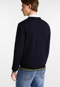 Marineblauer Strickpullover mit rundem Halsausschnitt, ausgestattet mit grünen und marineblauen gestreiften gerippten Bündchen und Saum. Die Silhouette zeigt eine lässige Passform.