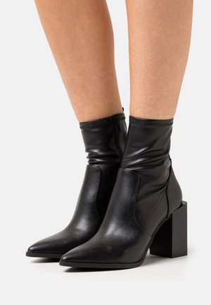 Black leather ankle boots with a pointed toe and block heel. Features a gathered texture around the ankle and a zip closure at the back.