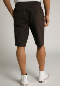 Brune bomulds shorts med elastisk talje, baglomme detaljer og lige snit, parret med hvide high-top sneakers.
