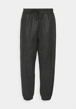 Svarte joggebukser laget av teksturert stoff, med elastisk midje med snore, sidelommer og smale mansjetter.
