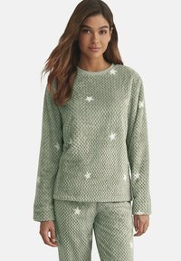 Ensemble de pyjama en polaire vert avec une surface texturée, comprenant un haut à col rond et un bas assorti, ornés de motifs d'étoiles blanches.