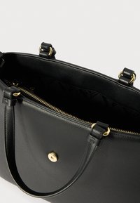 Sac à main en cuir noir avec quincaillerie dorée, surface texturée, deux poignées, ouverture zippée et un intérieur spacieux.