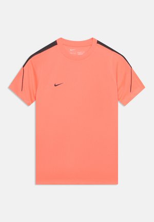 Koraalkleurig sportshirt met korte mouwen, een zwart Nike-logo op de borst en zwarte strepen langs de bovenkant van de mouwen.