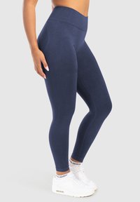 Marineblå högmidjade leggings gjorda av stretchigt tyg, med en slät yta och ribbad detalj längs sidorna.