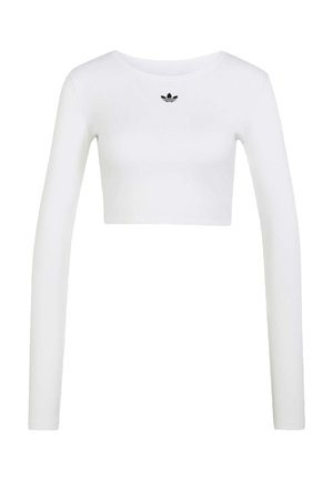 Bílý krátký top s dlouhým rukávem, kulatým výstřihem a malým černým logem Adidas umístěným uprostřed pod lemem krku.