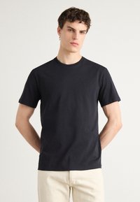 Black cotton t-shirt with a round neckline and short sleeves. Features a subtle logo on the chest and a classic fitted design.