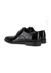 Chaussures habillées en cuir noir poli avec un bout arrondi, un laçage et un talon bas. Texture lisse et peu de détails sur les côtés.