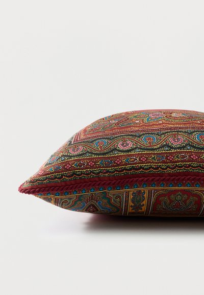 Coussin carré avec des motifs complexes cachemire et floraux en rouge, bleu, rose et or, bordé d'une garniture tressée rouge.