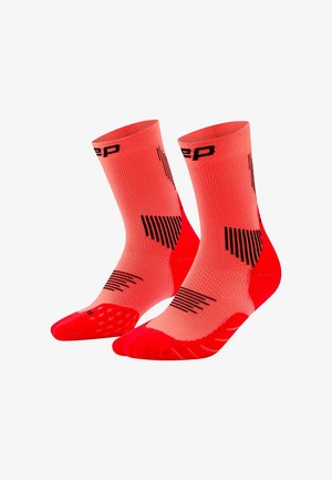 Paar leuchtend roter Sportsocken mit schwarzen geometrischen Mustern und einem Logo nahe der Oberseite, vor weißem Hintergrund dargestellt.