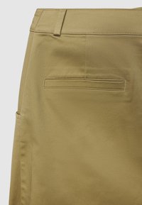 Pantaloni kaki con texture liscia, dotati di una tasca posteriore e passanti per cintura, progettati per una silhouette aderente.