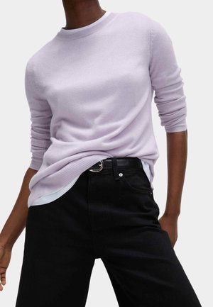 Suéter color lila claro con cuello redondo y mangas largas, con una textura suave. Combinado con jeans negros y un cinturón negro.