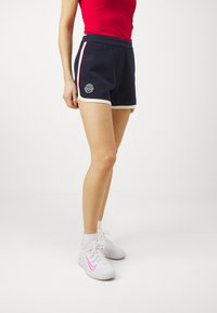 Marineblå shorts med hvit trim og brodert logo. Har et komfortabelt liv og sidestripe i rødt.
