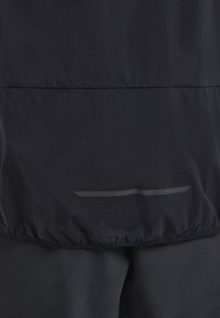 Dunkelblaues Jacket mit einer glatten, leichten Textur. Verfügt über einen reflektierenden, horizontalen Streifen und einen elastischen Saum an der Taille.