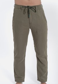 Olivine lniane spodnie dresowe z elastycznym pasem, regulowanym sznurkiem, bocznymi kieszeniami oraz zwężanym krojem nogawek.