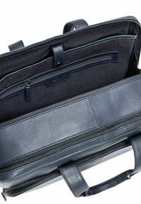 Ciemnoniebieska skórzana torba o teksturowanym wykończeniu, z wieloma zapinanymi na zamek kieszeniami i uchwytem do noszenia.