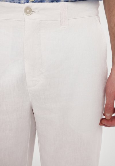 Pantalons en lin de couleur claire avec une texture lisse, dotés d'une fermeture à bouton et de poches latérales. Le design est ajusté et simple.