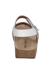 White sandal with a cork wedge heel, adjustable ankle strap, and smooth leather upper. Simple design with a flat footbed.