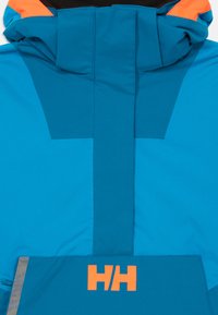 Giacca outdoor blu e verde scuro con accenti arancioni e una patta frontale che presenta il logo "HH" di un vivace arancione.