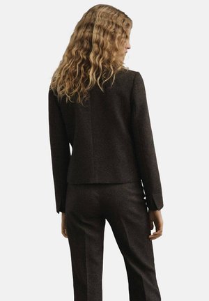 Chaqueta marrón a medida hecha de tejido texturizado, con un diseño ajustado, mangas largas y un espalda corta, combinada con pantalones a juego.