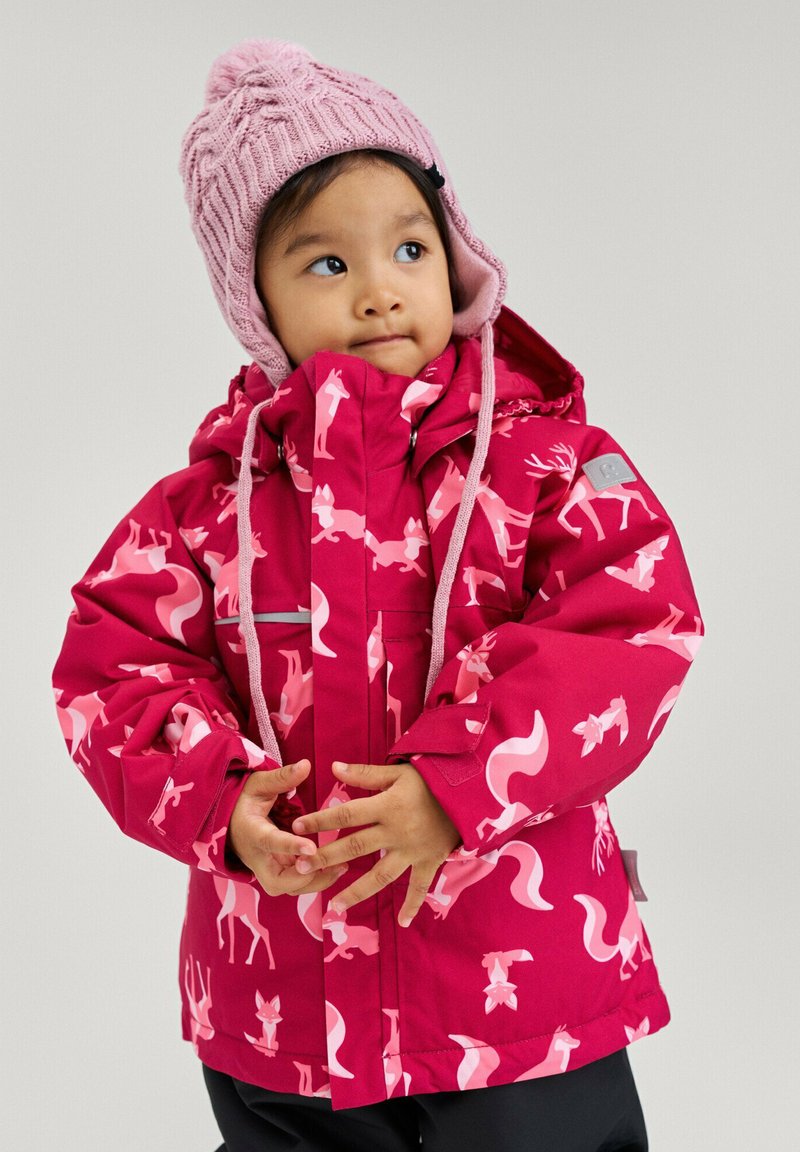 Pink winter jacket featuring a playful animal pattern, with a hood, zippered front, and elastic cuffs. Worn with a light pink knitted hat.