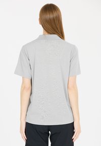Grå kortärmad polotröja med krage, tillverkad av slätt tyg. Har en enfärgad design utan mönster, fotograferad bakifrån.