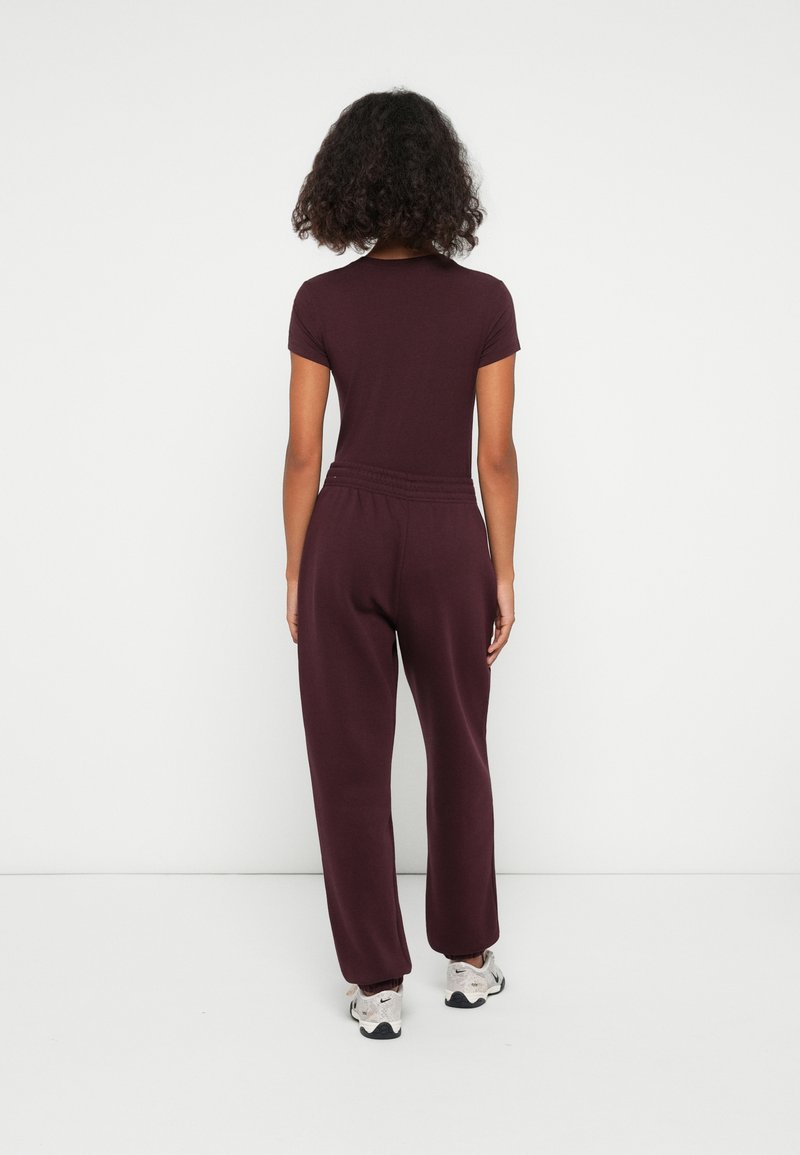 Completo bordeaux composto da un top aderente a maniche corte e pantaloni larghi, realizzato in un tessuto morbido con una cintura elastica.